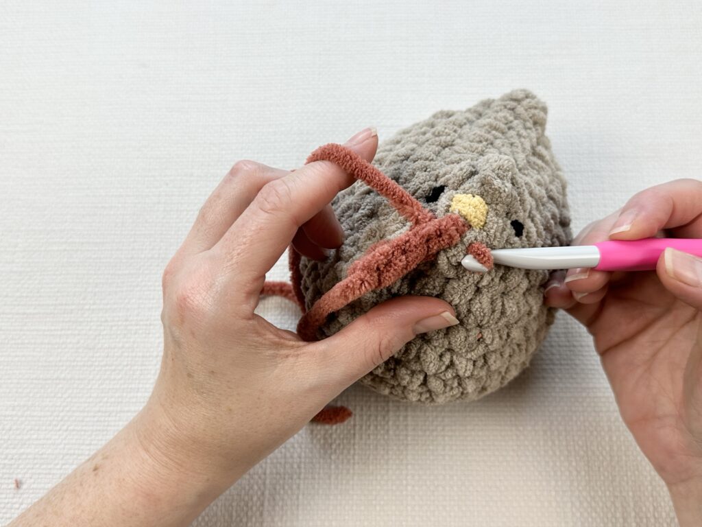 Hands crocheting a rooster modification onto the original Mabel chicken pattern. 