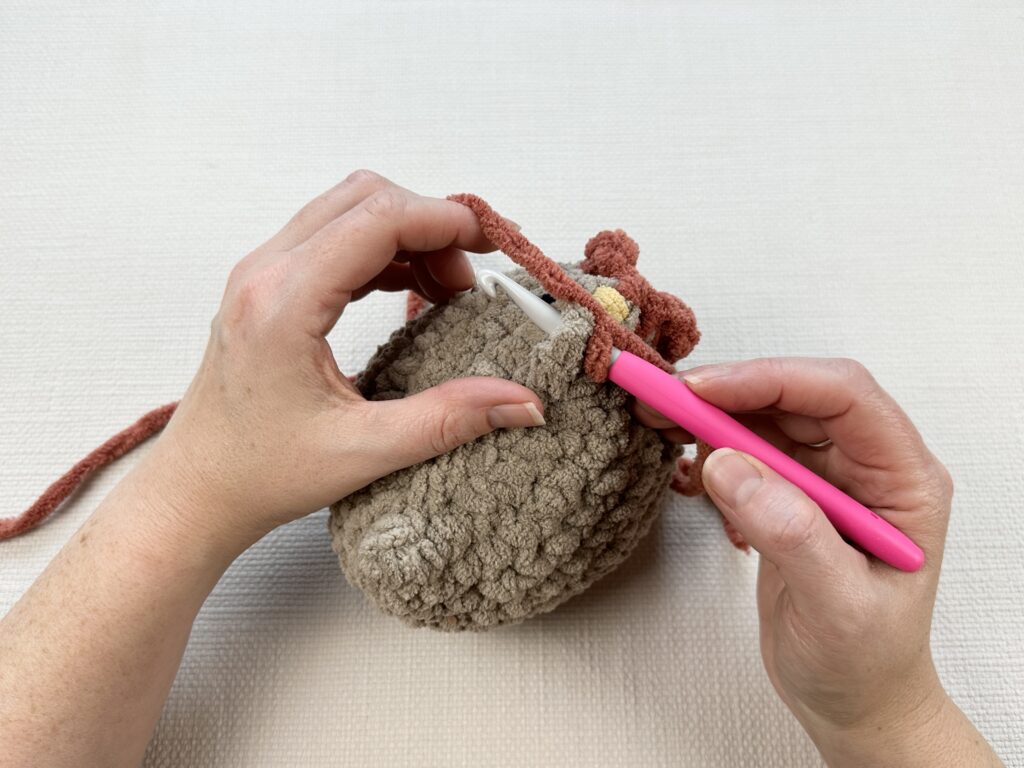 Hands crocheting a rooster modification onto the original Mabel chicken pattern. 