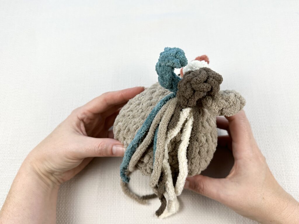 Hands crocheting a rooster tail on the original Mabel chicken pattern. 