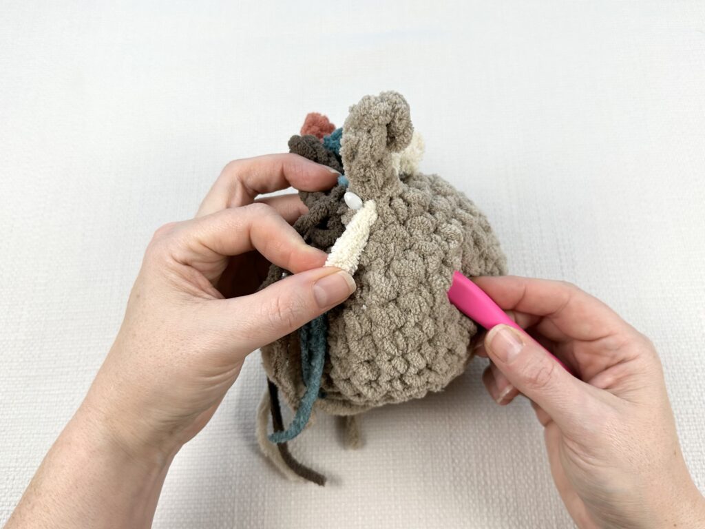 Hands crocheting a rooster tail on the original Mabel chicken pattern. 