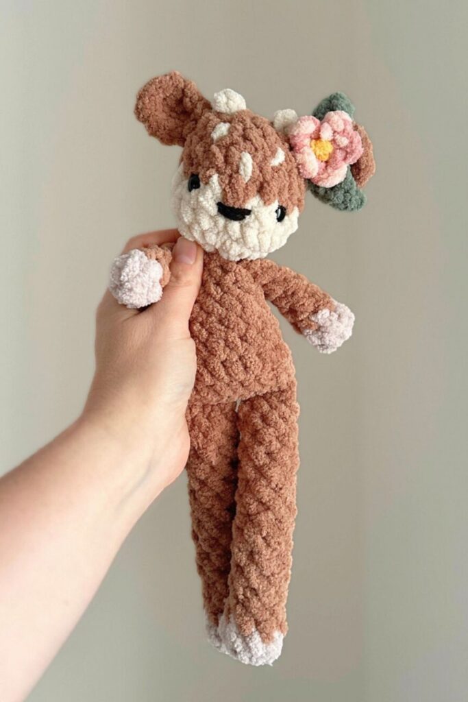 Hand holding crocheted bunny with flowers in it's hair.