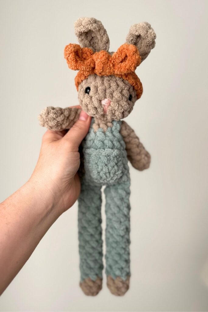 Handing holding crocheted bunny with a headband on.