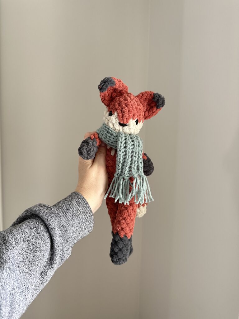Crocheted fox with a cozy crochet scarf on.