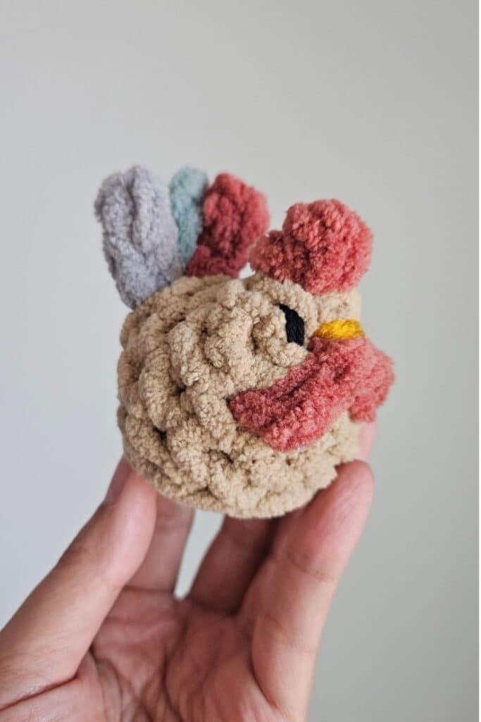 Side view of a small crocheted rooster.