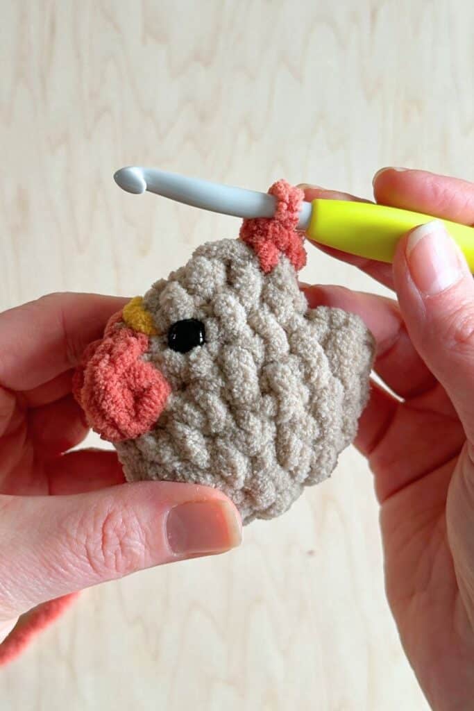 Close up of a crochet hook forming the rooster's comb.