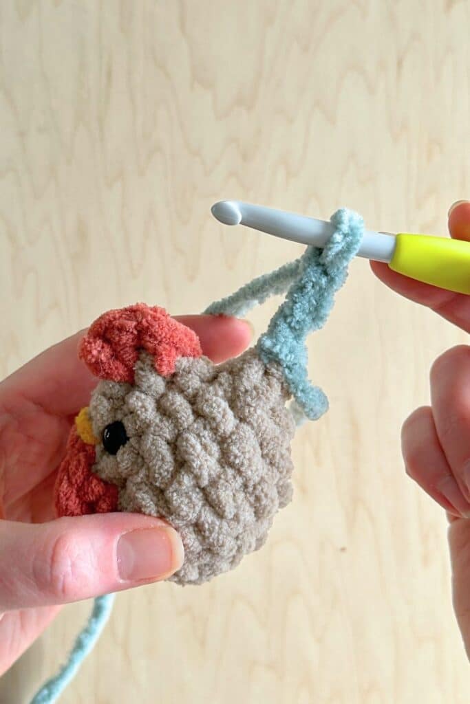 Close up of a crochet hook in the second step of making the rooster's tail feathers.