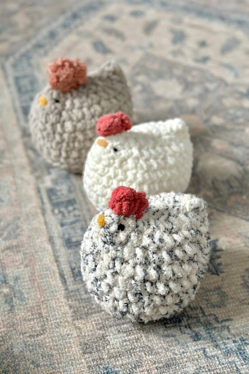 Three crochet chickens on a farmhouse rug.