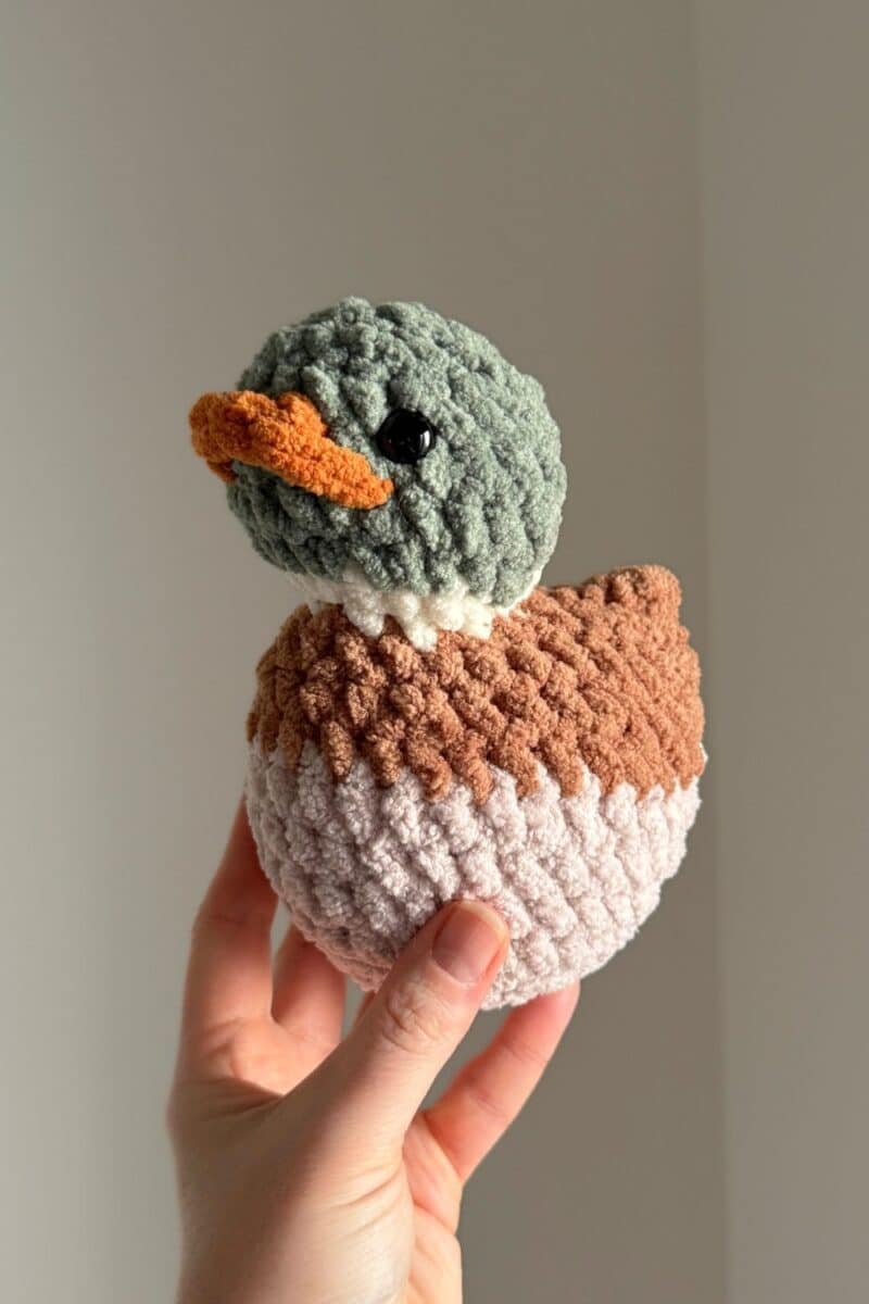 A crochet mallard duck in a hand.