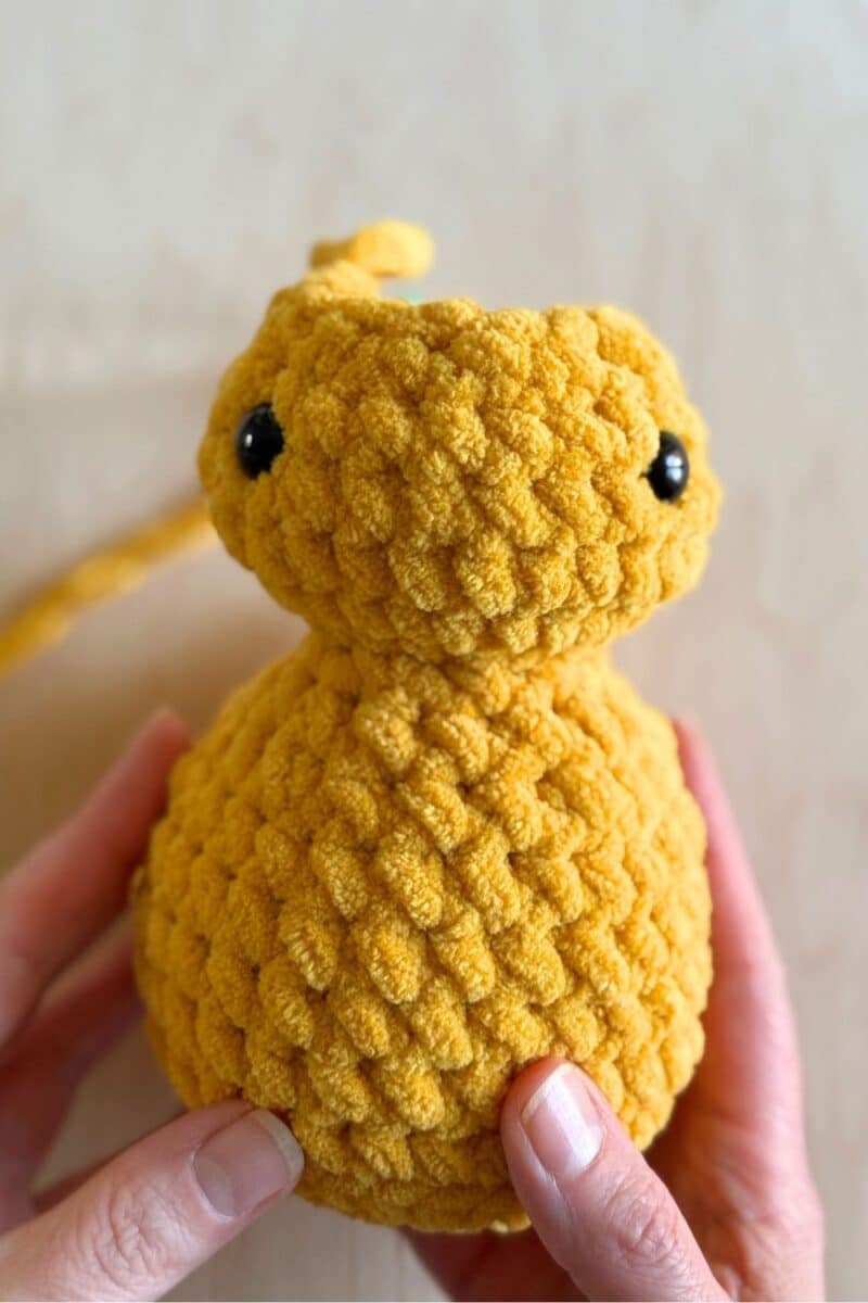 A process photo of a yellow crochet duck. Eyes have been added to the head.