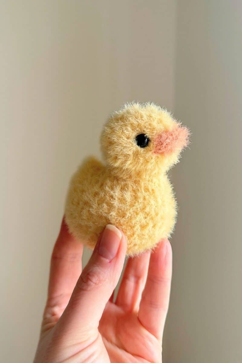 A fuzzy little crochet duck in a hand.