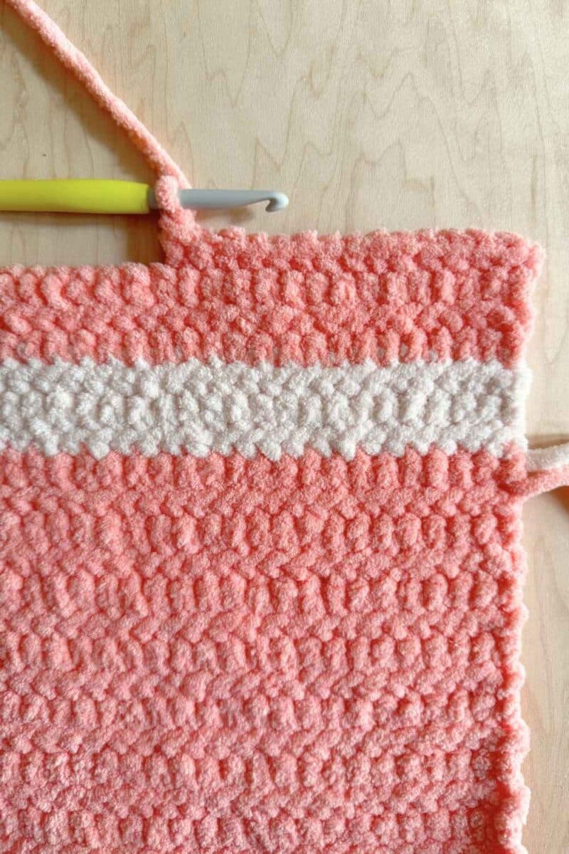 Process photo showing pink yarn with a half-row to start the pillow of the sleeping bag.