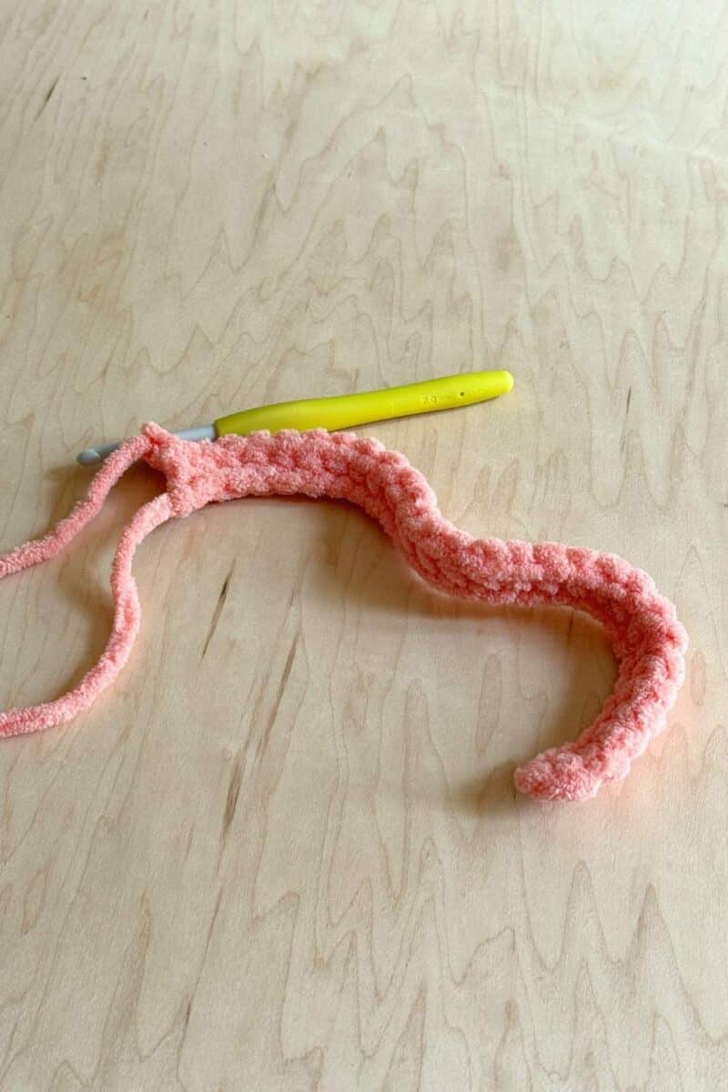 Pink yarn crocheted into a chain and the first row of the pattern.