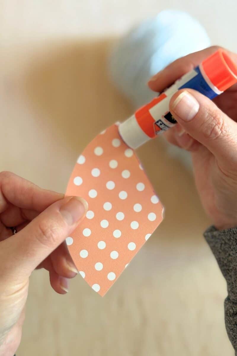 Instructional photo of adding glue to the cardstock birthday party hat.