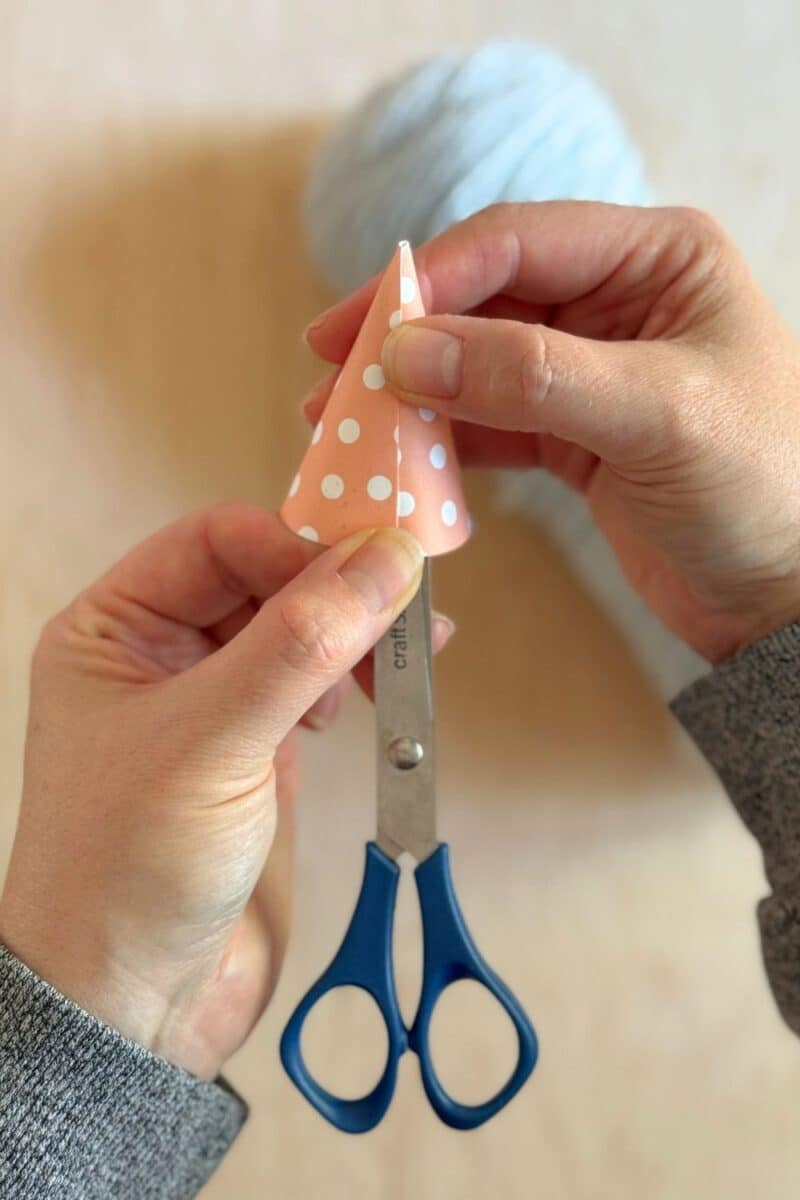 Hands holding a paper party hat closed while it dries. 
