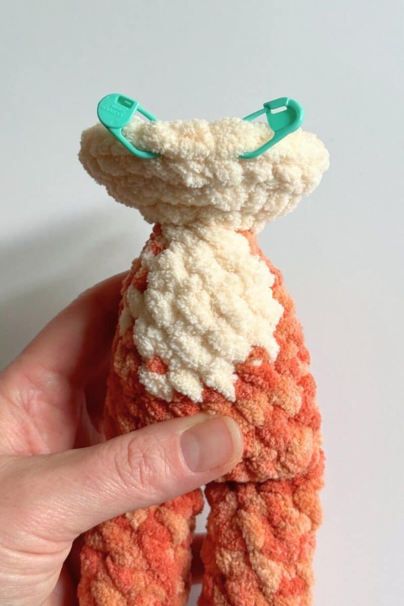 Process photo of the crochet cat with stitch markers indicating where the bobble stitches will go.
