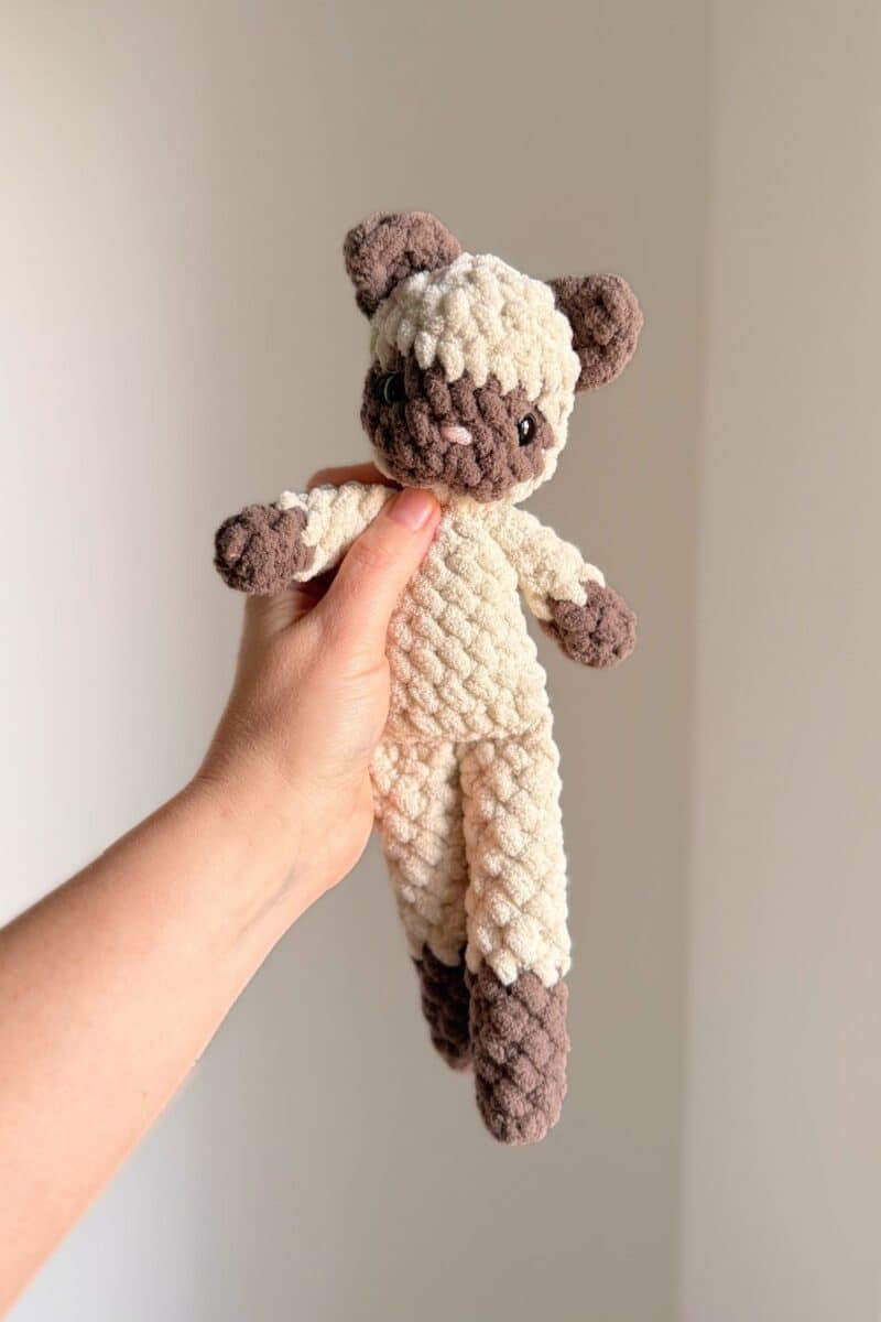Hand holding a crochet siamese cat.