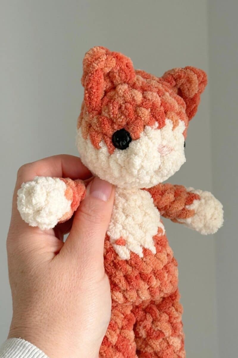 Close-up image of on orange crochet cat with larger eyes and a cute, shaped mouth and nose.