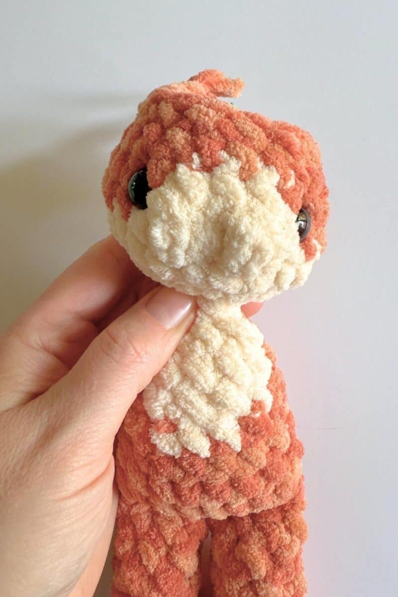 Hand holding a partially finished crochet cat.