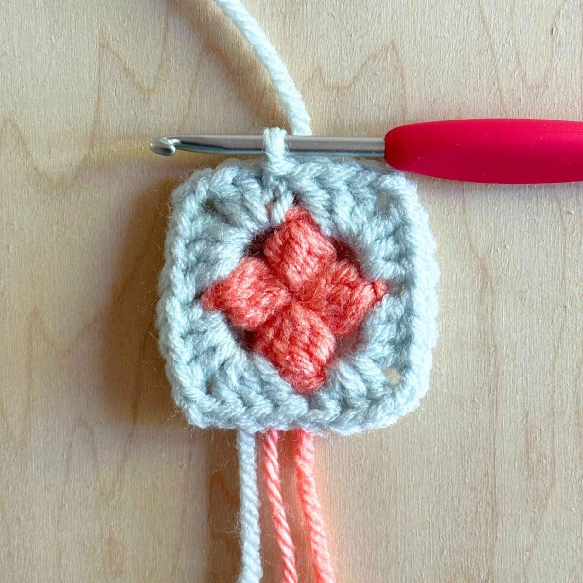 Last step (shown in blue yarn) of making round 2 of the crochet square.