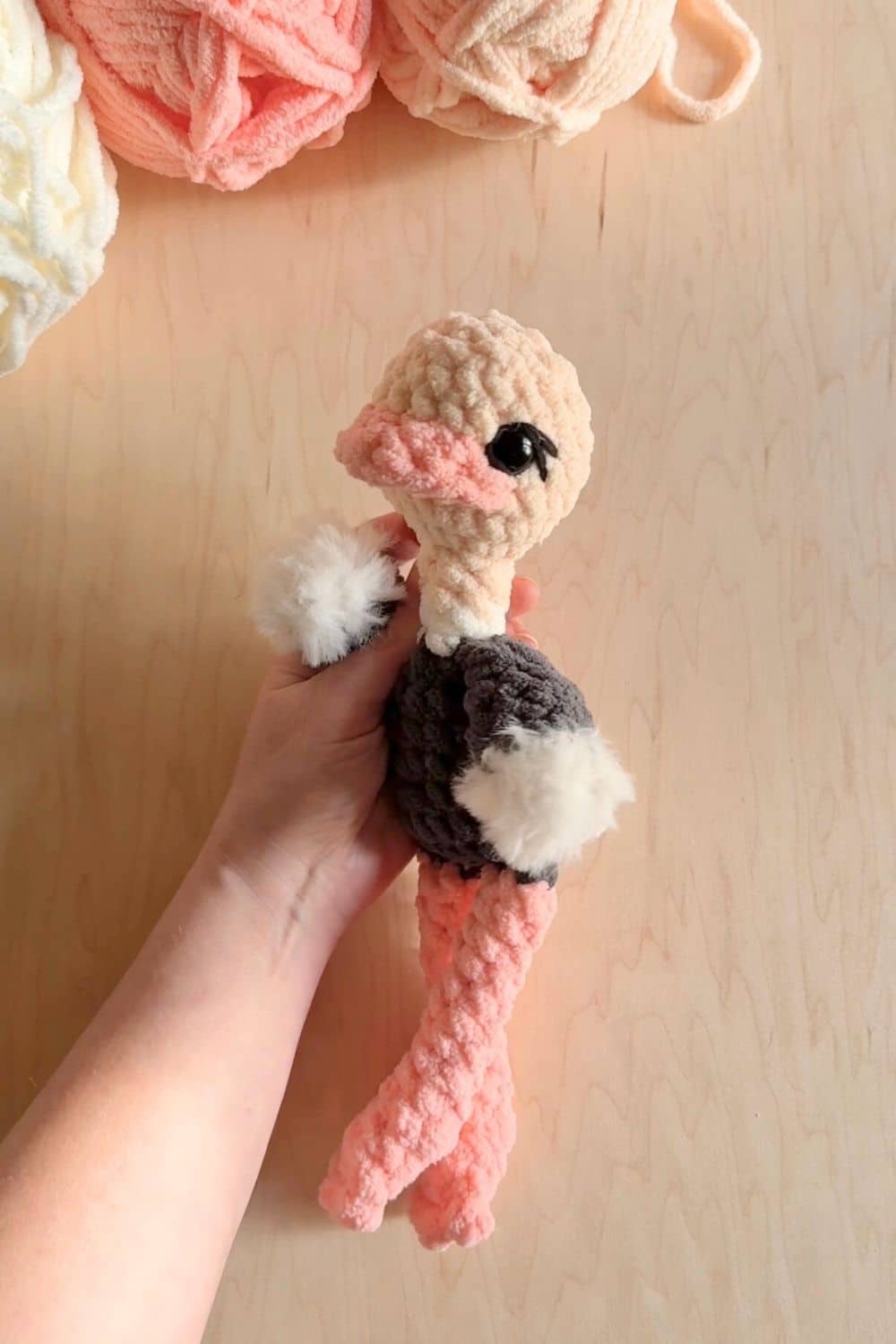 A hand holding a crochet ostrich.