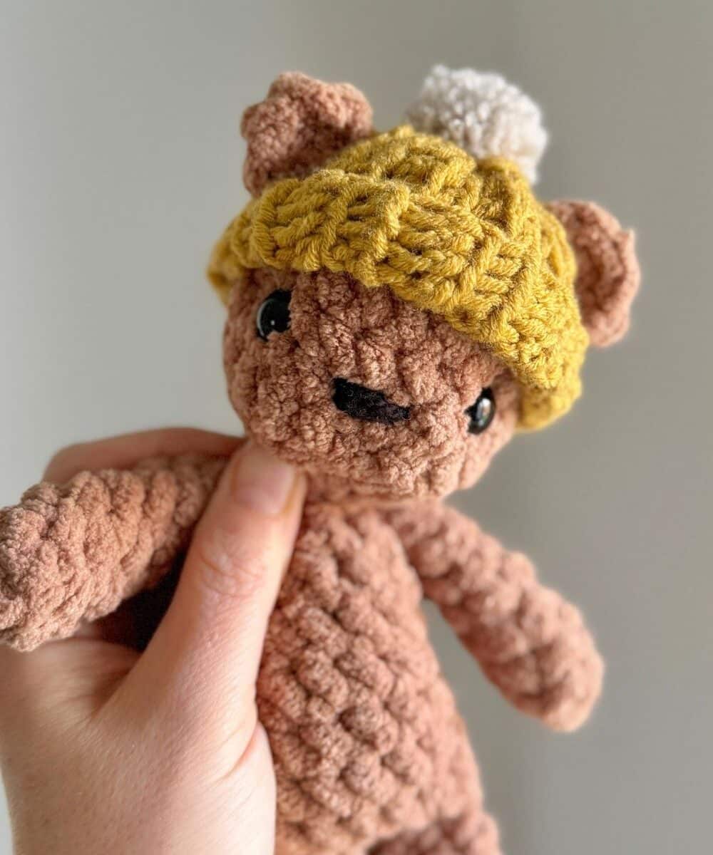 Crochet bear wearing a yellow crochet beanie hat.