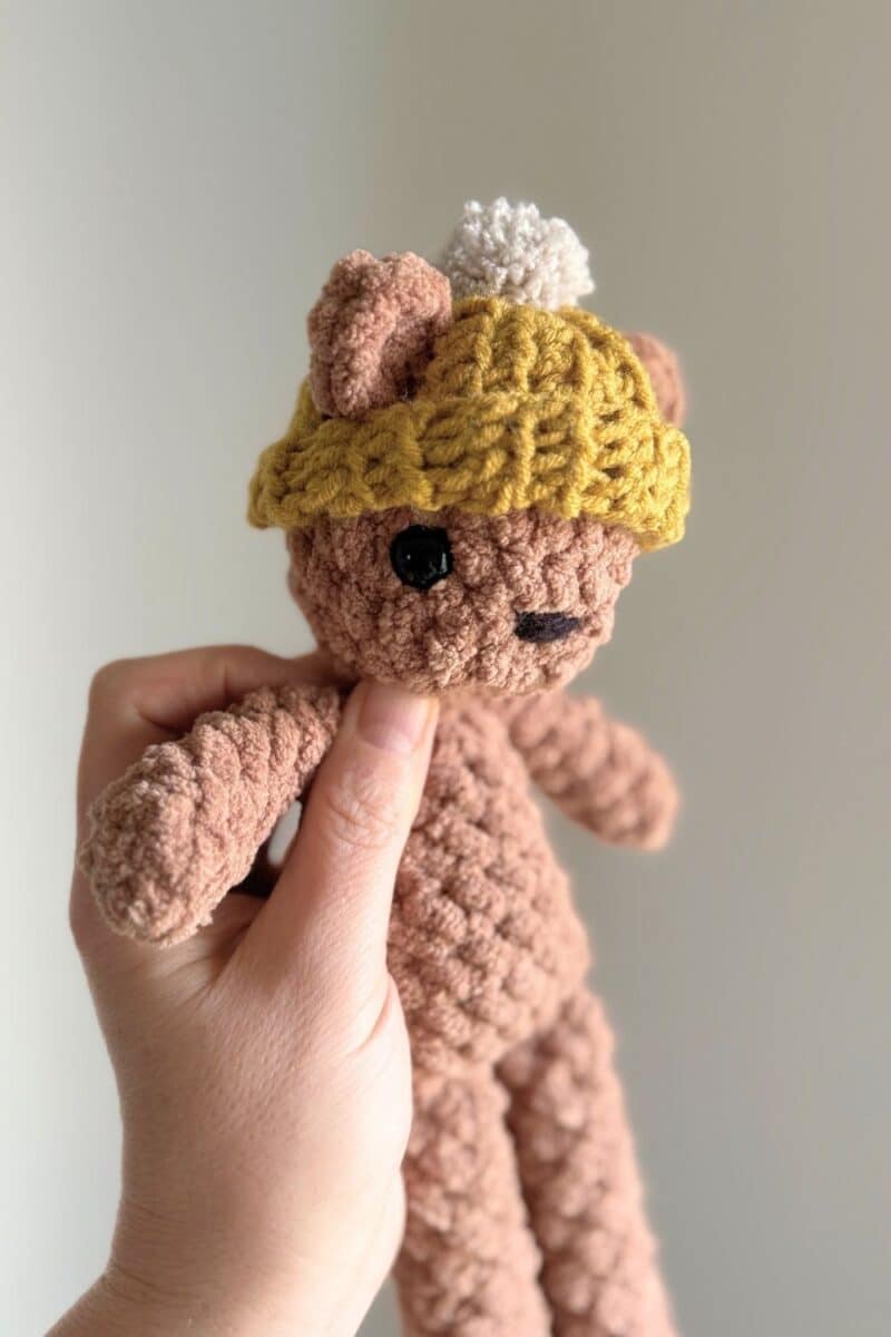 Finished yellow hat with a grey pom pom on a little brown crochet bear.