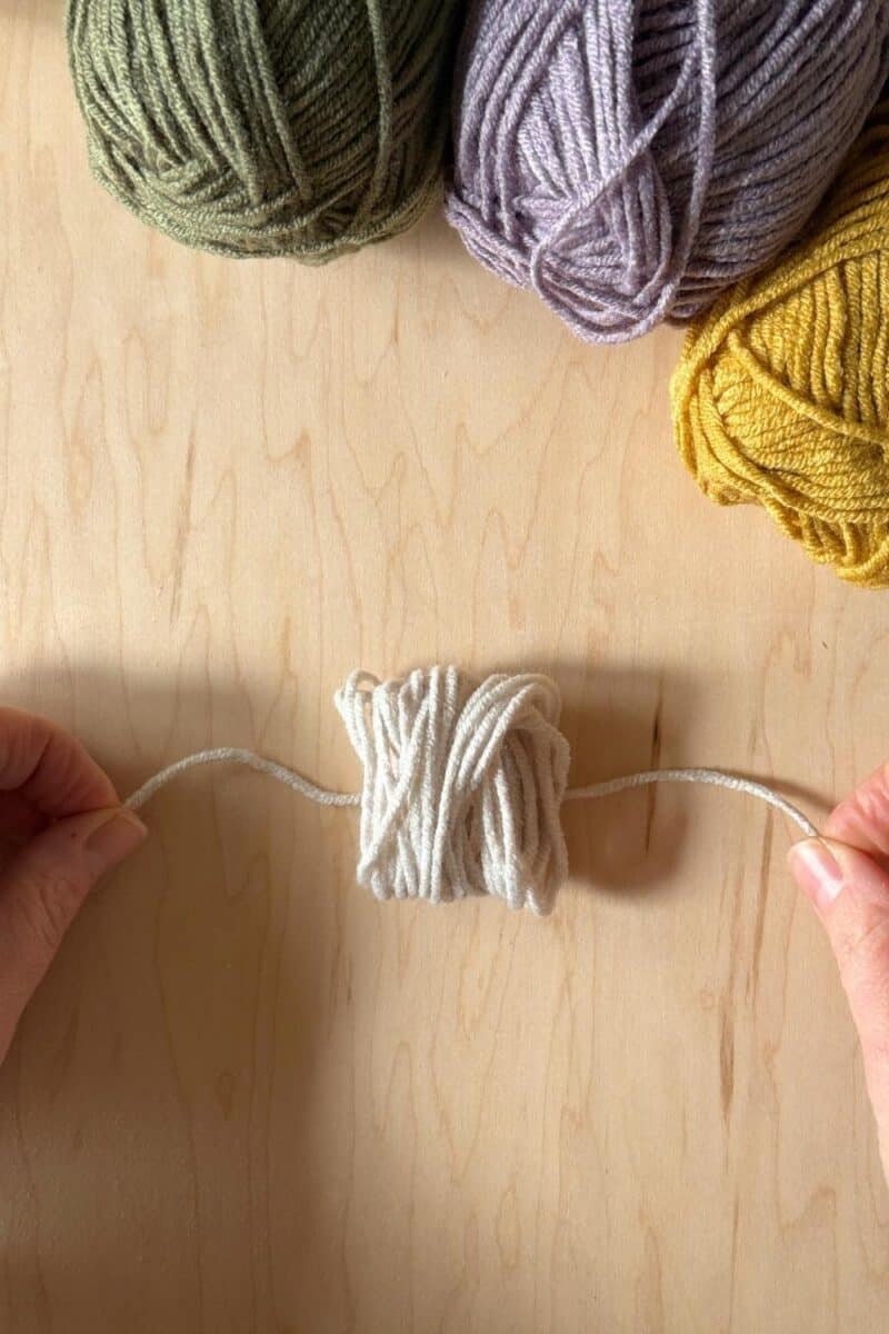 Woven yarn laying on top of a 10" strand of yarn.