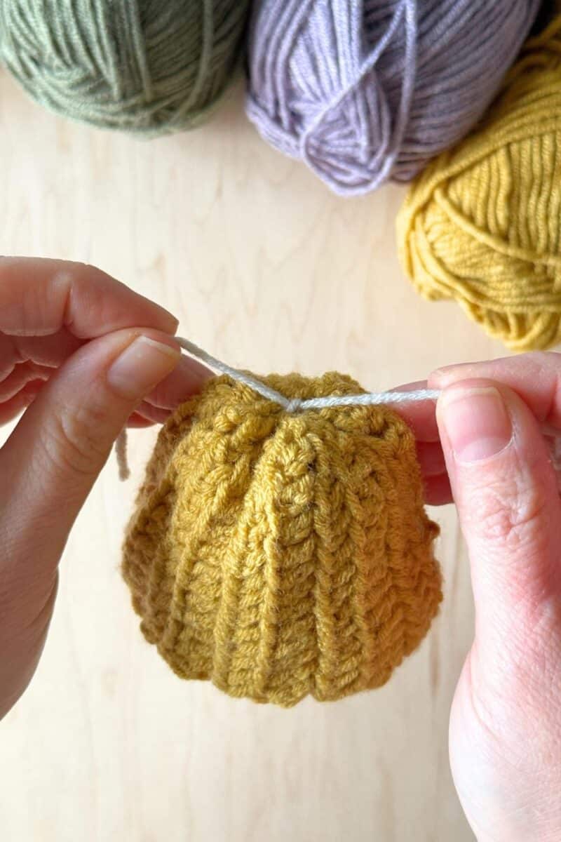 Hands showing the inside of the hat - knotting ends together.