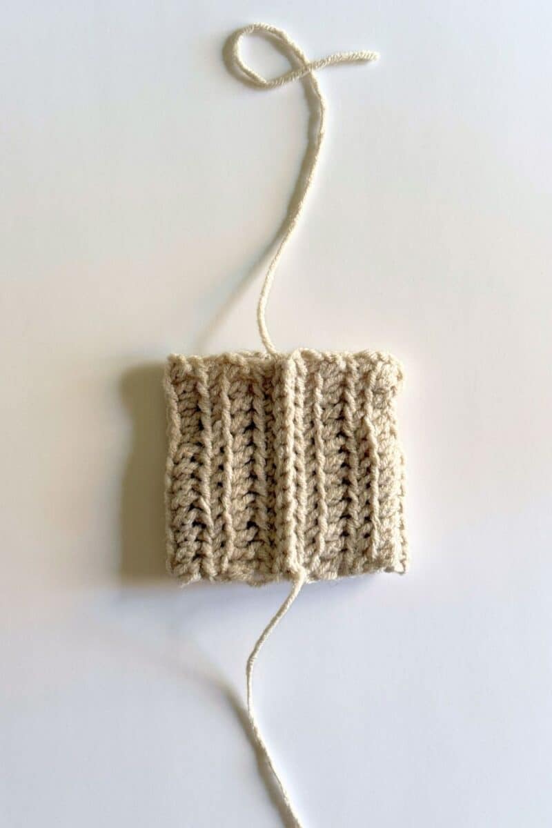 Process photo showing the beanie hat slip stitched closed with strands at top and bottom.