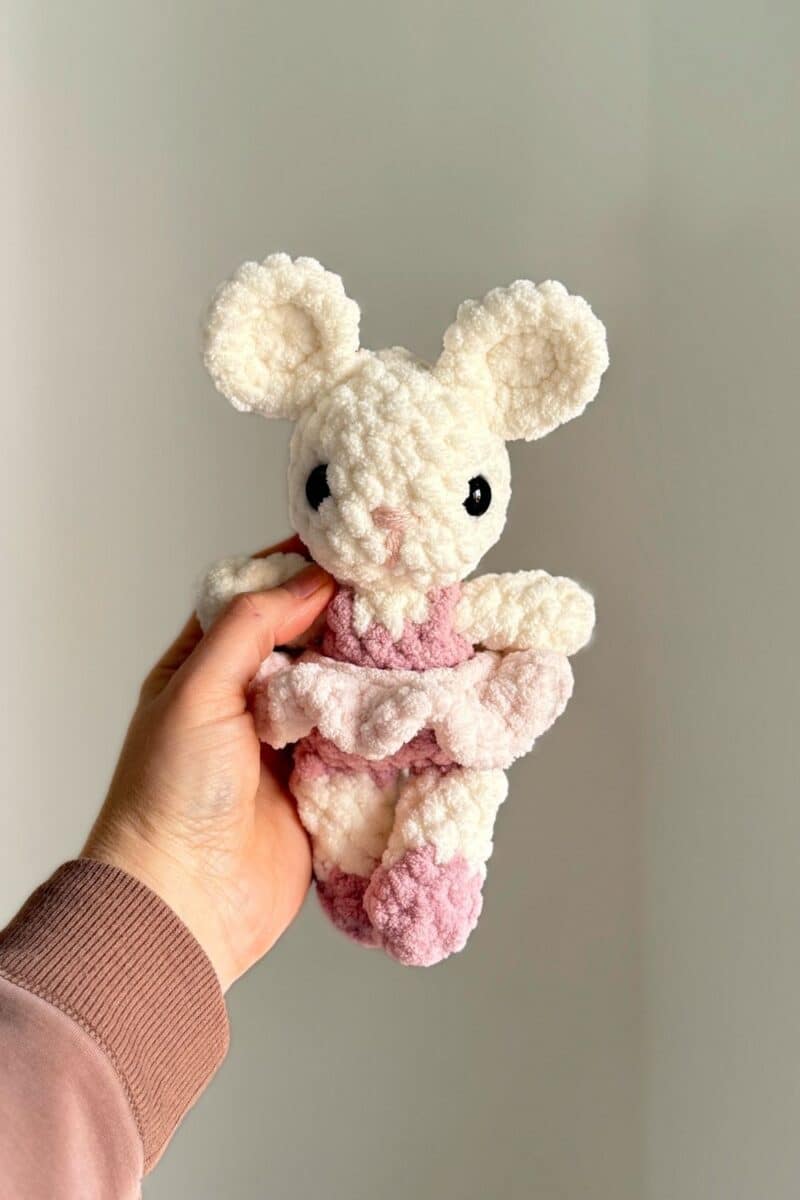 Hand holding a pink baby crochet ballet mouse.