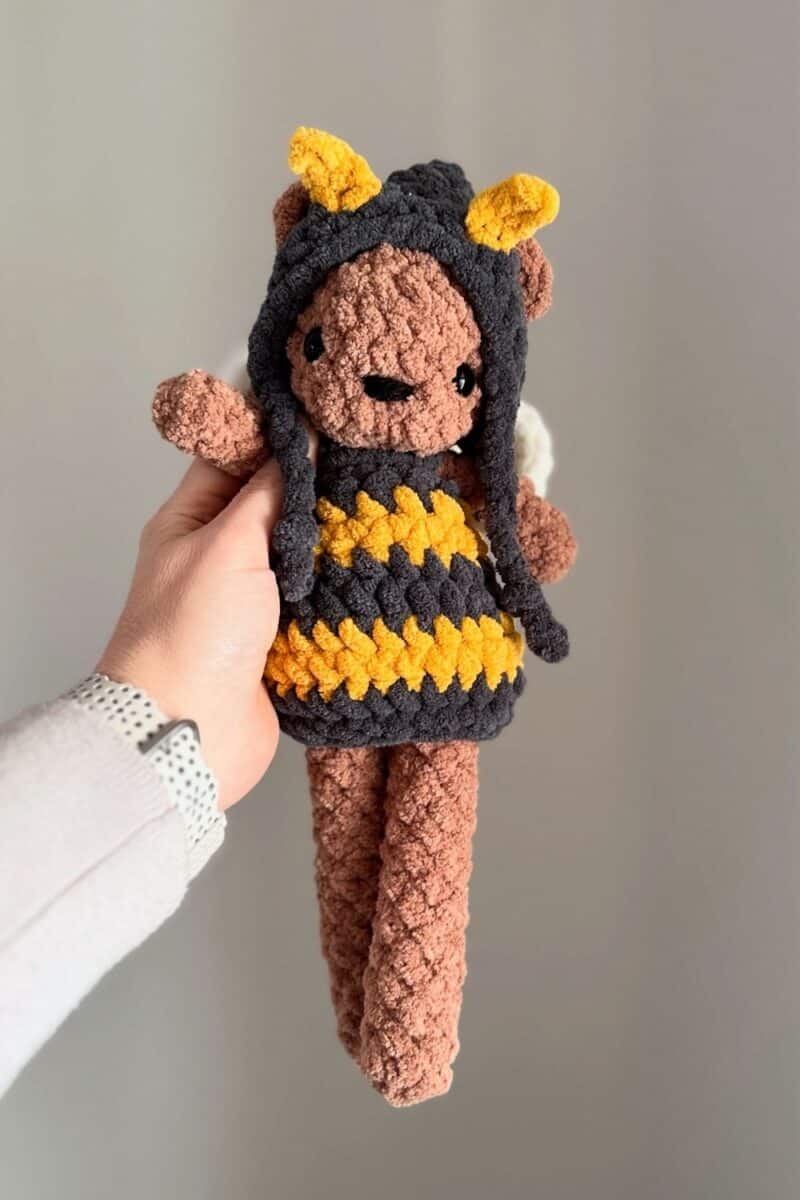Hand holding a little crochet bear wearing a crochet bee outfit.