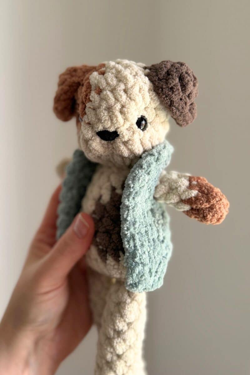 A spotted crochet dog wearing a vest.