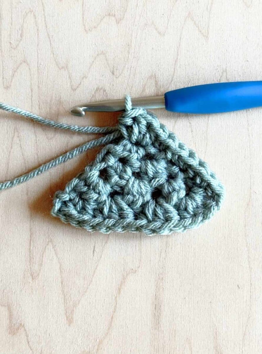 Second process photo for adding a finishing edge to the neckerchief pattern. Shows three stitches into the top of the triangle.