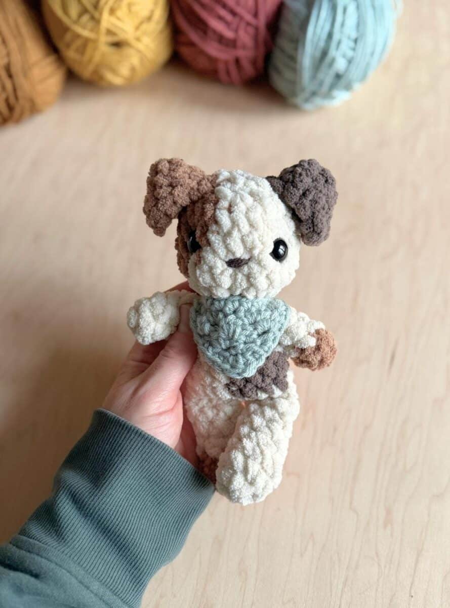 A crochet baby spotted puppy wearing a red neckerchief.