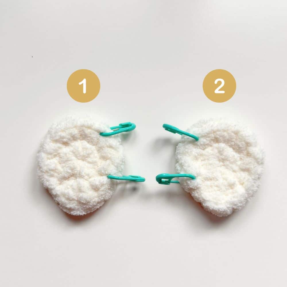 Two crochet goose wings with stitch markers.