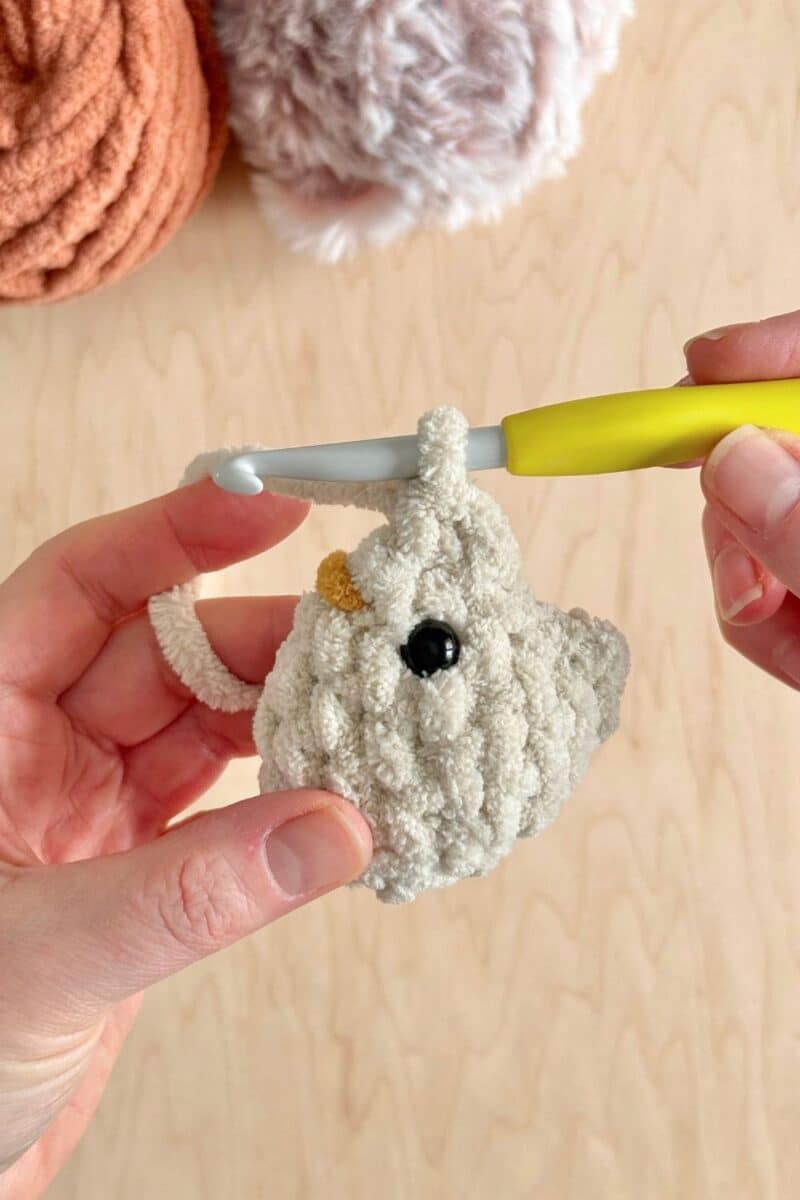 Two crochet stitches completed on the top of the chicken head.