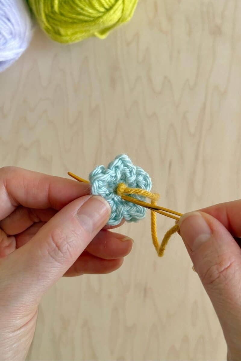 A yarn needle weaving the end into the center.