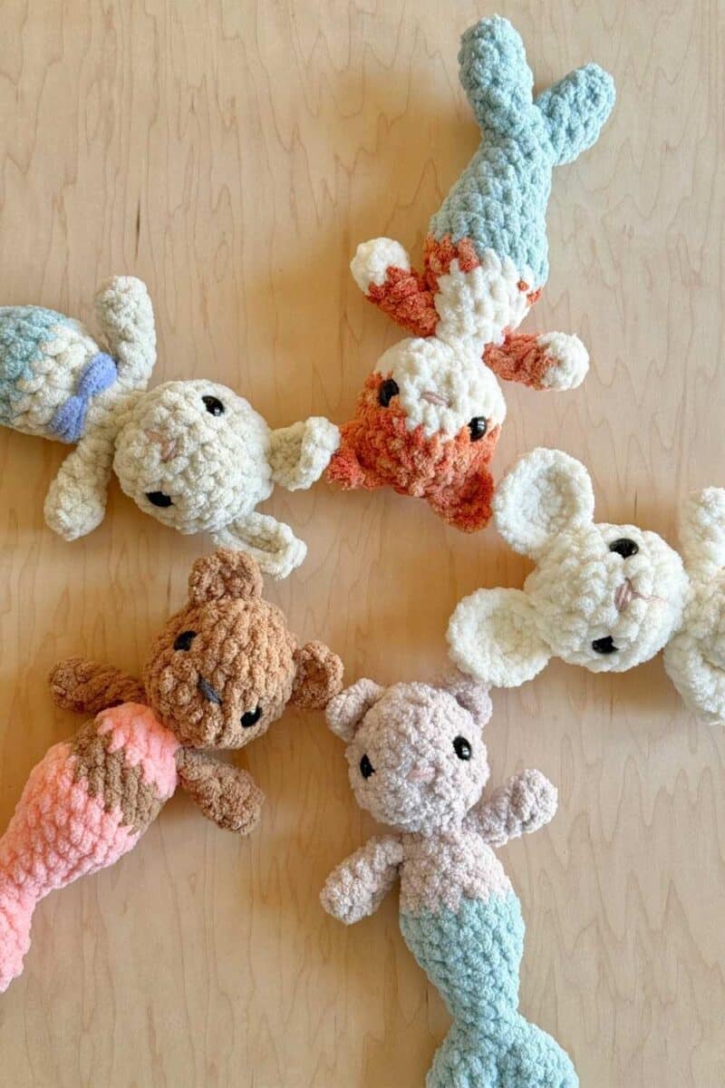 5 crochet mer-babies on a wood surface with their heads together in a circle.