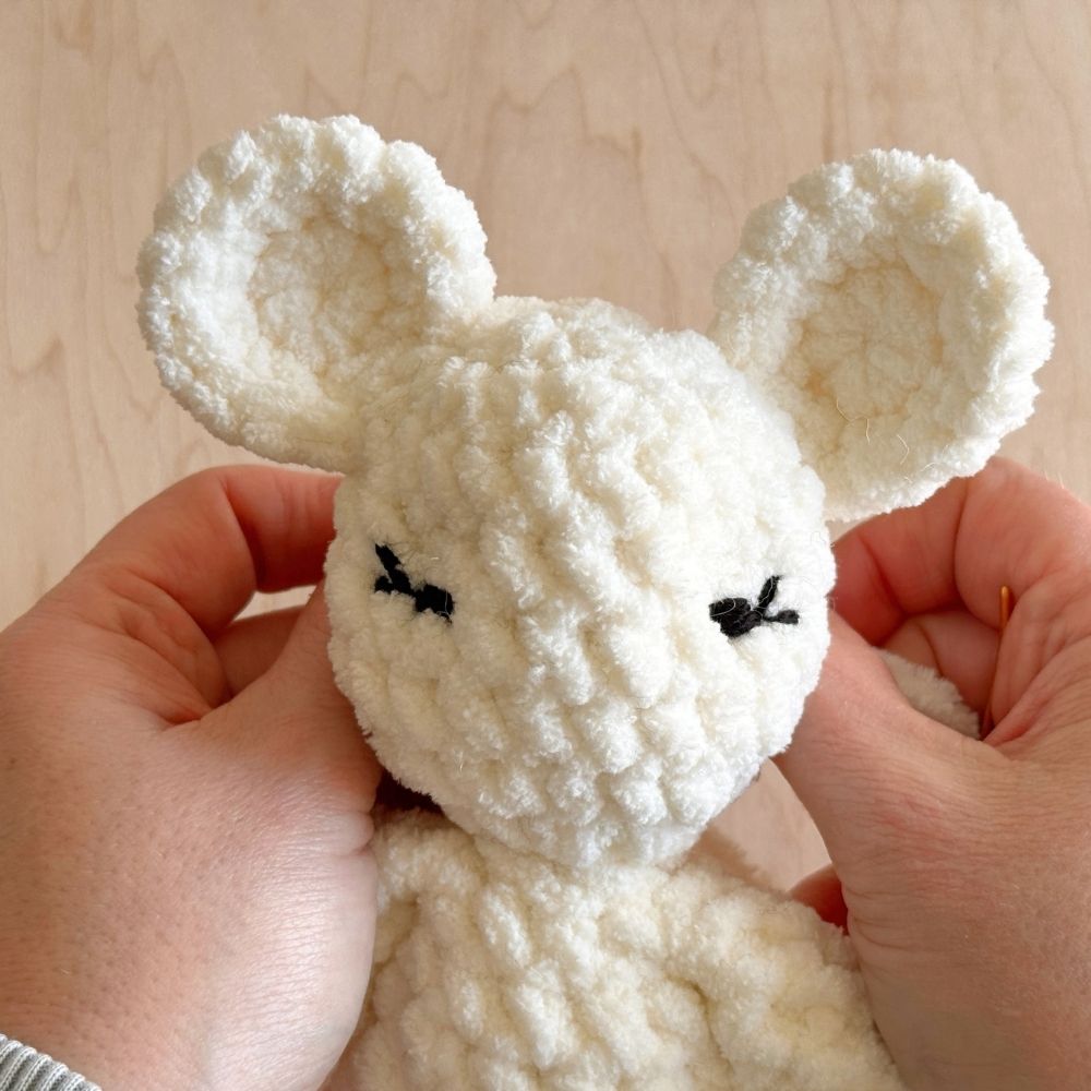 Pulling the yarn to shape the eyes on a crochet mouse.
