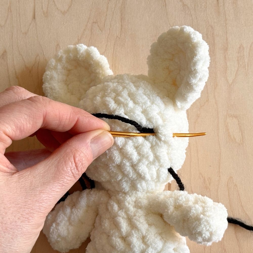 Showing steps for embroidering the eye on a crochet mouse.