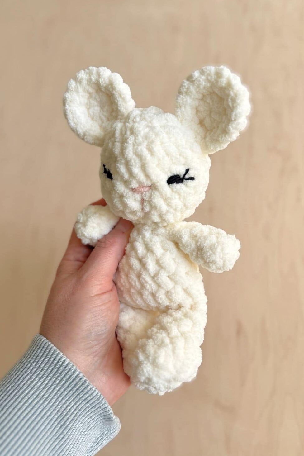 A finished white crochet mouse with embroidered eyes.