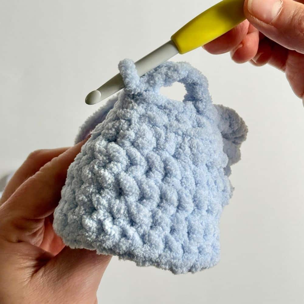 Process photo showing how to add the arm holes to a crochet dress.