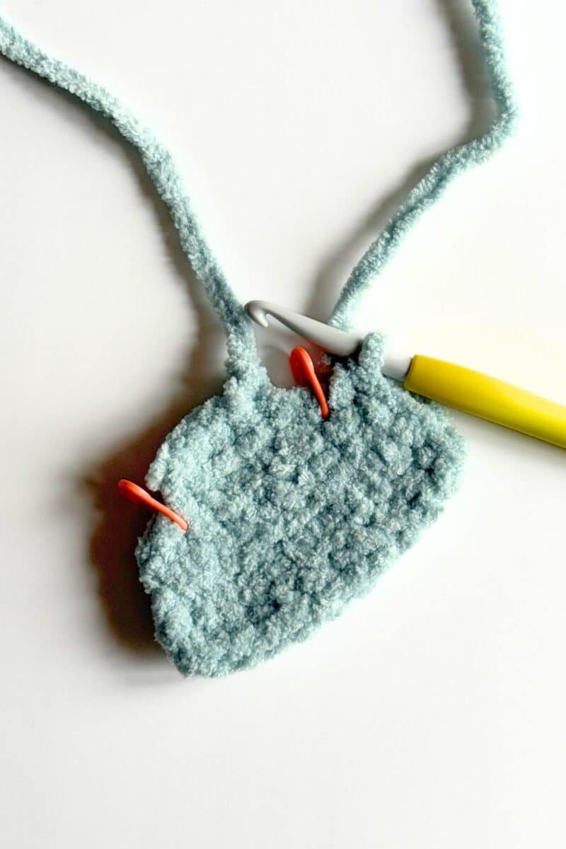 Second process photo of vest with stitch markers indicating arm holes.