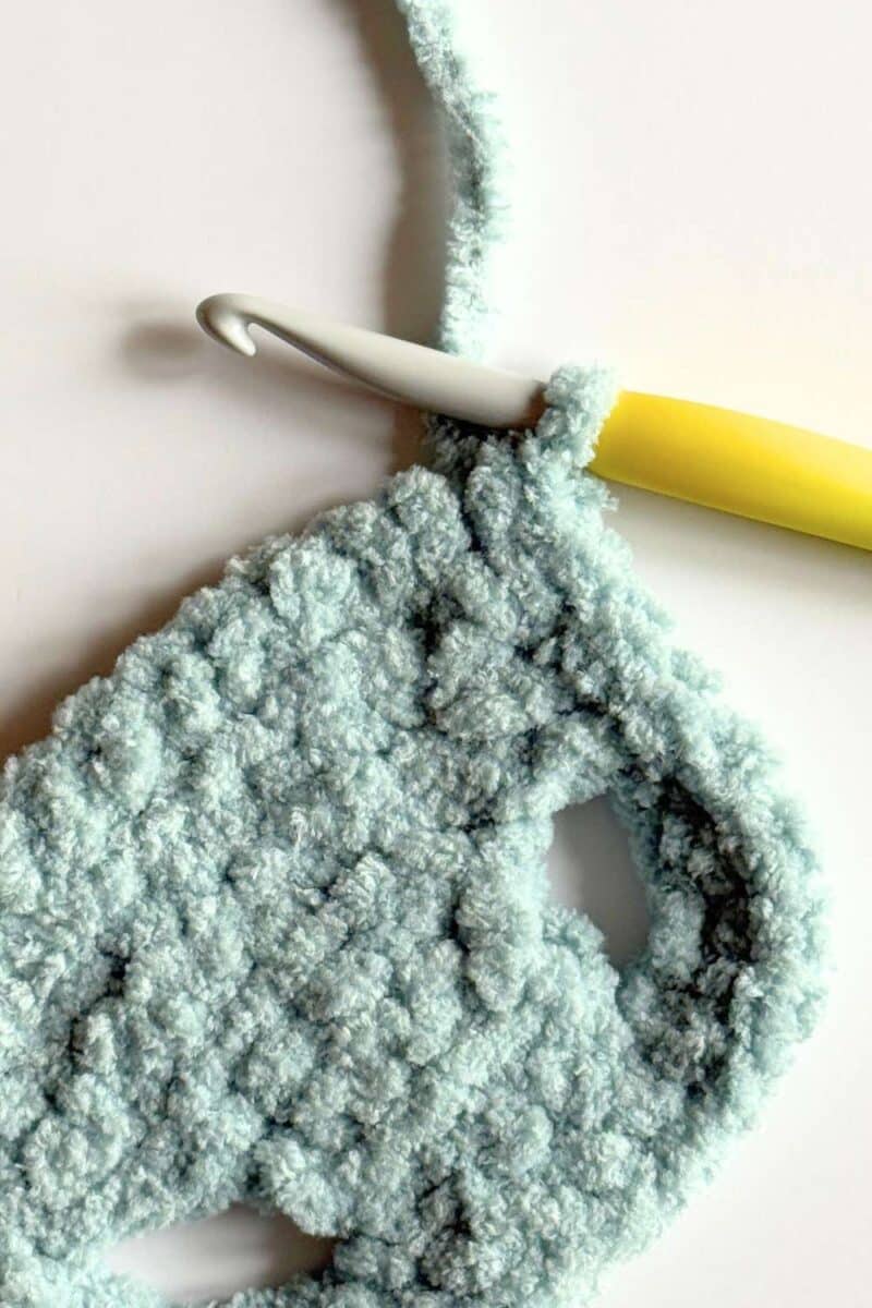Close up of crochet vest - smoothing out the corner with a stitch.