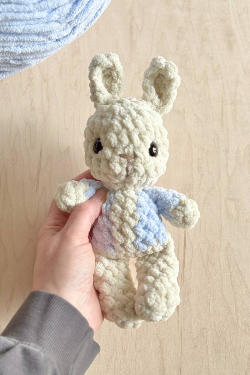 A crochet bunny wearing a blue jacket.