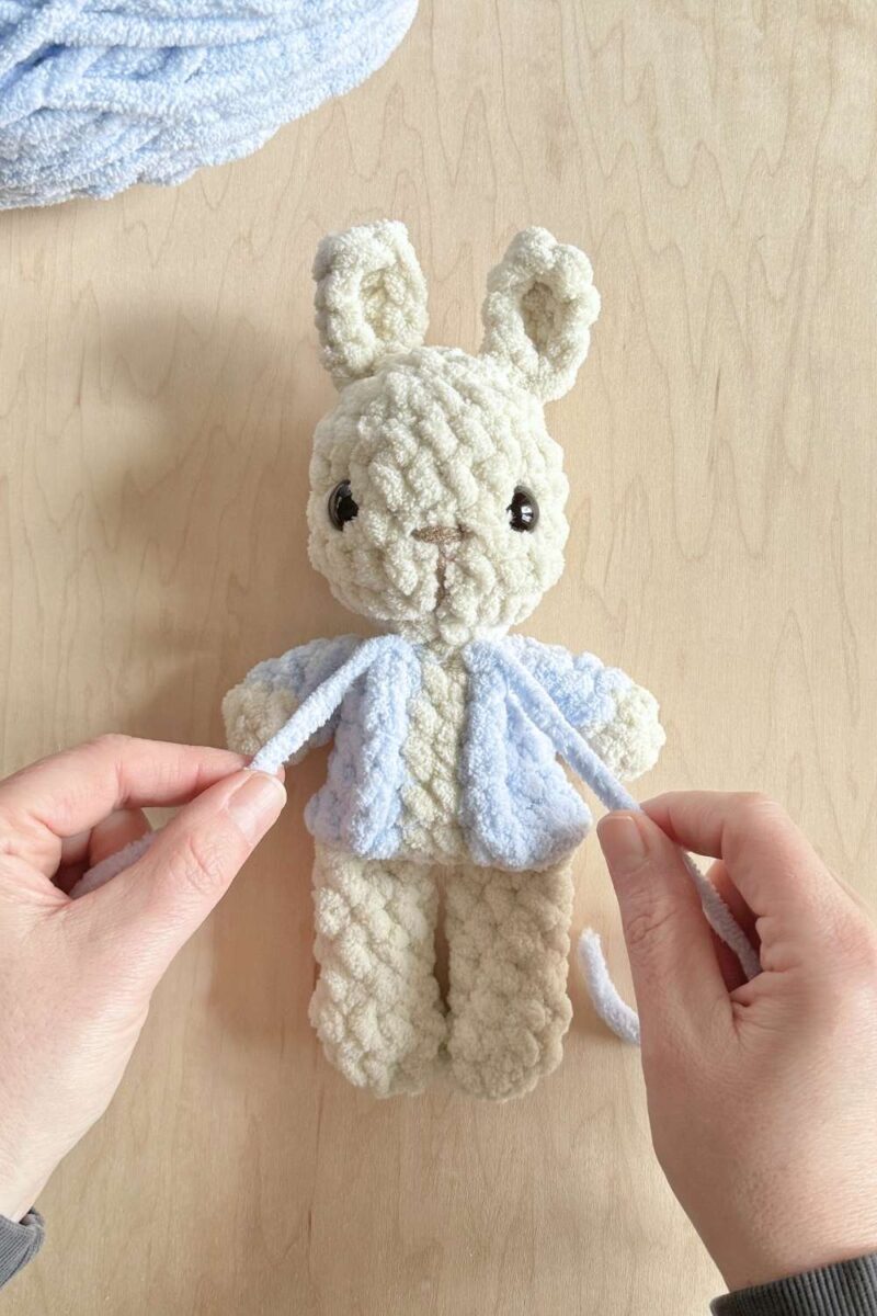 Jacket completed, hands holding finished yarn tails.