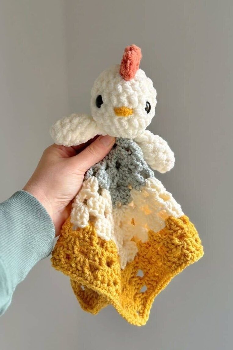 A crochet chicken lovey with bright colours - blue, white and yellow.