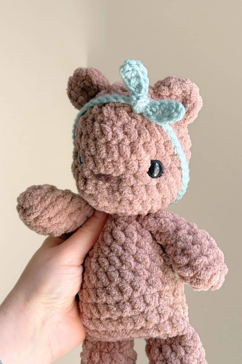 A light brown crochet bear wearing a crochet headband.