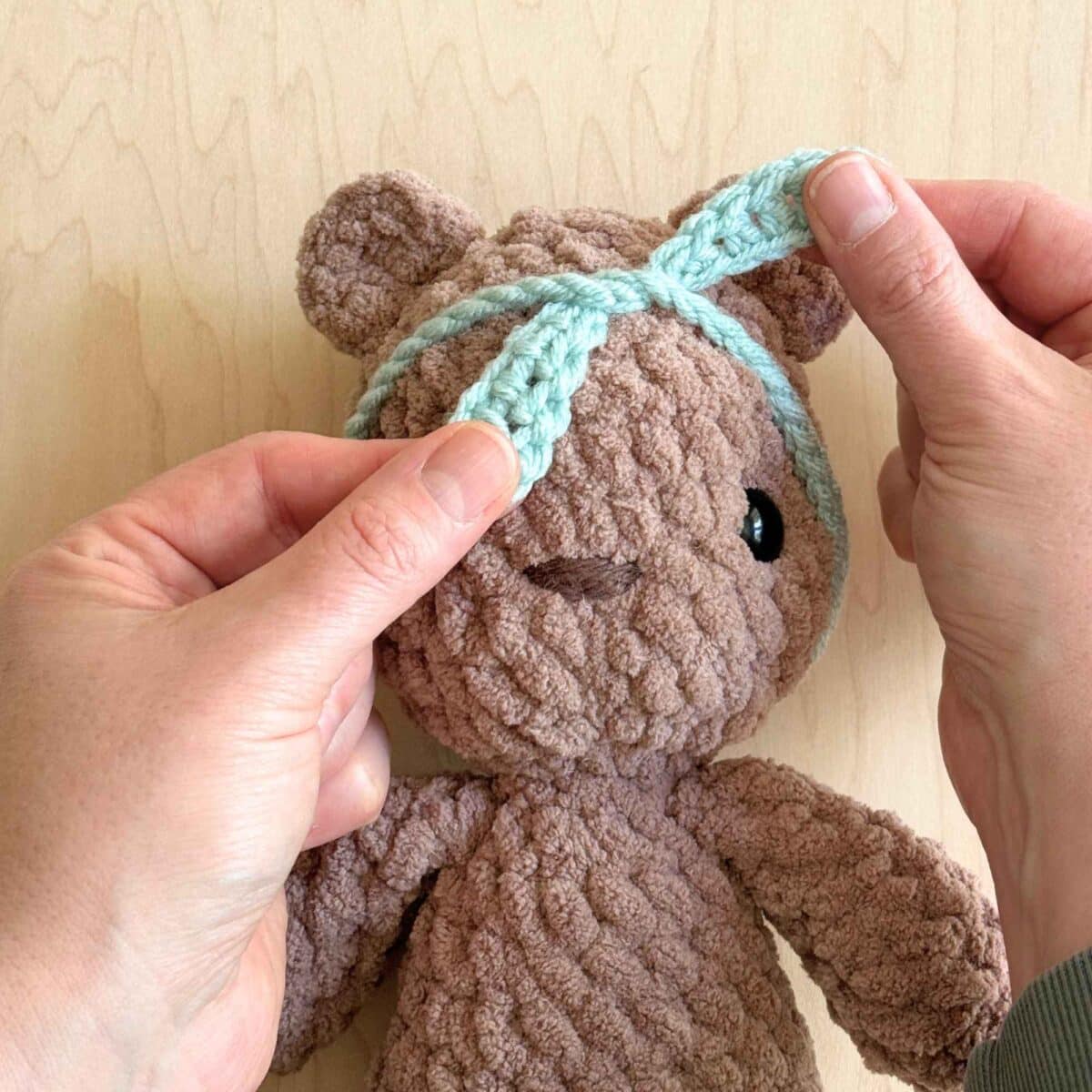 First steps of knotting the crochet headband onto the head.