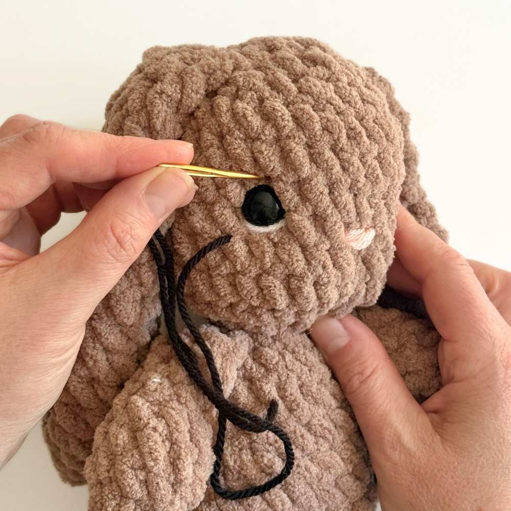 Process photo number 1 showing black yarn being added to the second eye to create the lash.